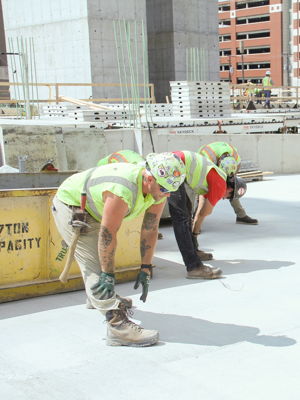 workers wearing ANSI-rated high-visability shirts, hard hats, steel-toe boots, and protective eyewear stretching before their shift on a job site
