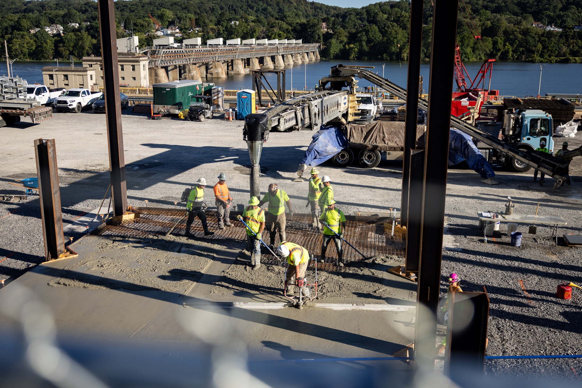 two worker carrying shovels walking along the highway towards their team working machinery to clear the shoulder of debris