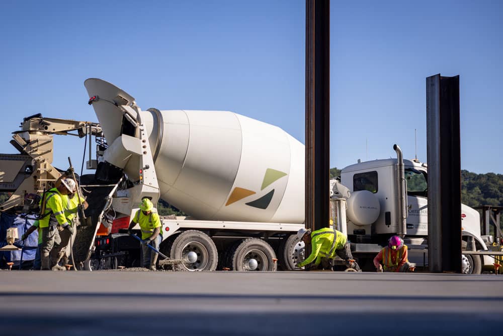 CBS worker spreading concrete in front of mixing truck